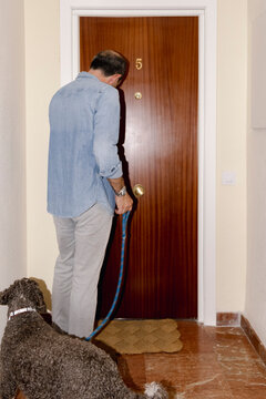 Anonymous senior dog owner entering apartment with curly companion