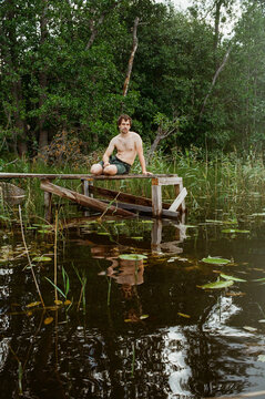 A Person Sits on a Wooden Platform Above the Water