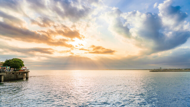 Golden sunset crepuscular rays over calm sea from Enoshima bridge