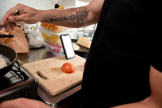 Cooking in a Kitchen With a Smartphone and Fresh Vegetables