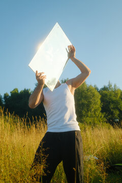 Person Holds a Mirror up to the Sun in Summer Nature Field