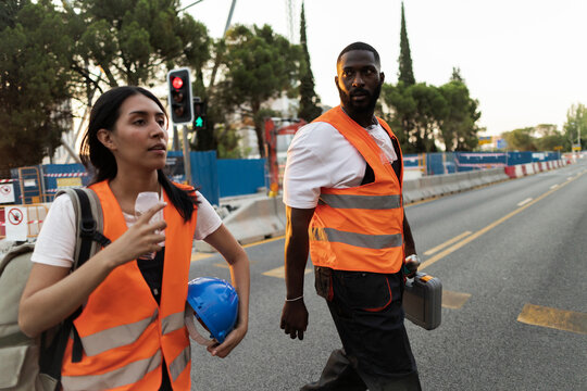 Construction workers walking on road with safety vests