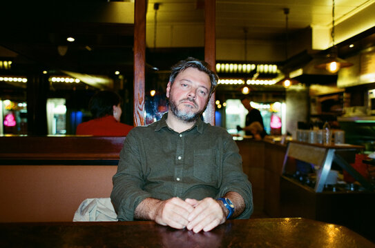 Man with clasped hands seated in a cozy pub