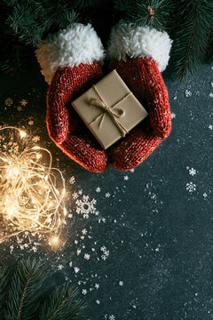 Hands in mittens holding Christmas gift