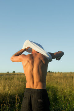 Man Taking off Shirt in Field During Daytime