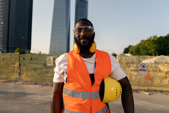 Confident african american construction worker holding hardhat smiling
