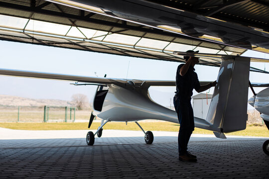 Pilot Performing Preflight Inspection on Light Aircraft in Hangar