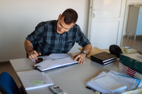 Man Working at Desk With Notebook and Map