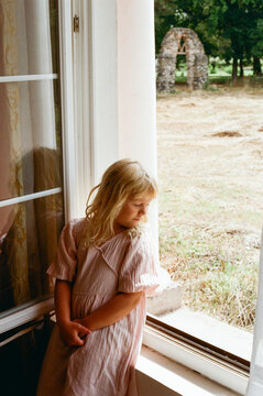 Girl Looking out of a Window in a Simple Setting During Daytime