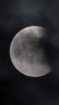 Lunar eclipse. The moon on the background of a dark sky with clouds.