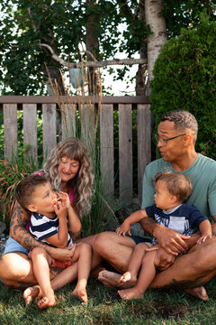 Candid family moment: parents with two young children in backyard