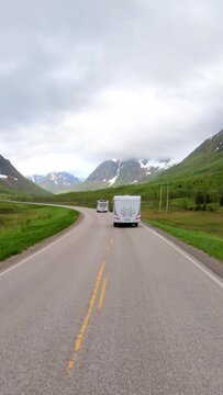 POV driving on a scenic mountain road in Norway with campers ahead.