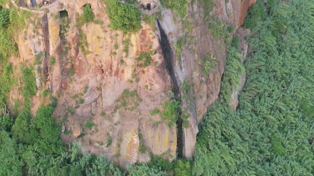 Aerial view of the steep rocky cliffs and lush green vegetation surrounding the historic village of Calcata, Calcata, Lazio, Italy.