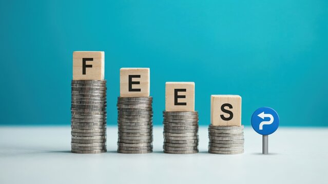 Wooden letter blocks spelling fees placed on declining stacks of shiny silver coins with a blue background