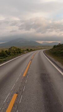 Empty road in Norwegian mountains at sunrise, vertical travel landscape.