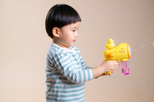 Cute toddler playing with an automatic bubble maker machine