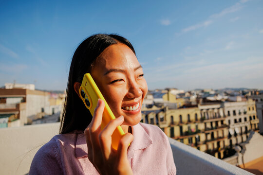 Woman enjoying call using smartphone on rooftop