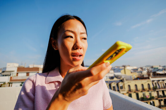 Woman sending voice message using smartphone on rooftop