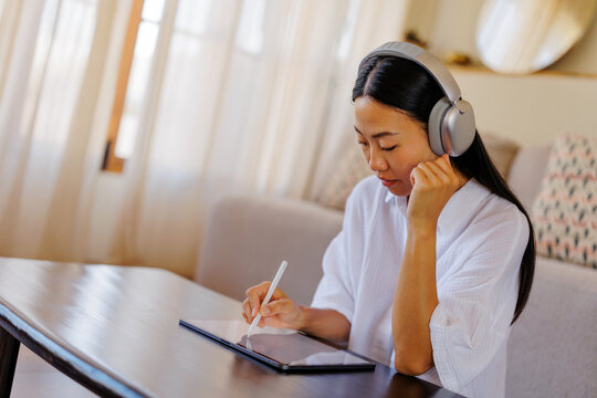 Woman listening to music drawing on digital tablet