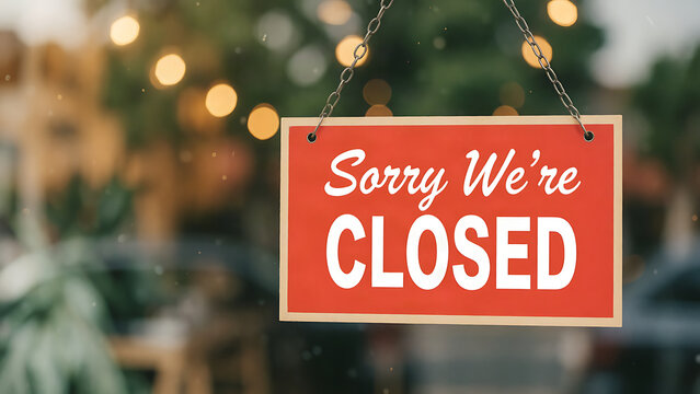 Red closed sign hanging on a window with blurred festive lights in the background
