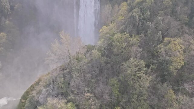 Aerial view of the cascading waters of Marmore Falls surrounded by lush forest vegetation in Terni, Umbria, Italy.