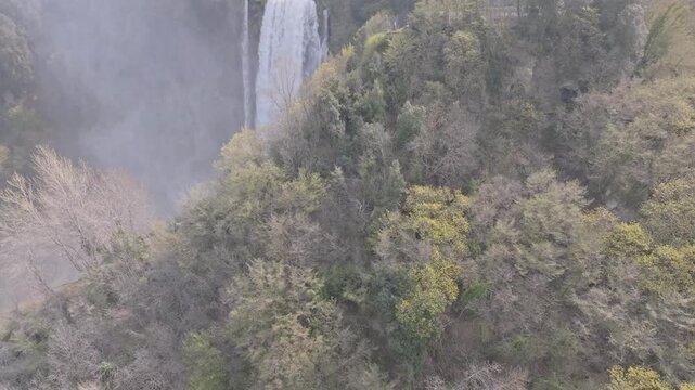 Aerial view of Marmore Falls cascading through lush green forests in the Umbria region of Terni, Umbria, Italy.