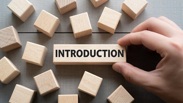 Hand placing wooden block with introduction text among scattered cubes on gray surface