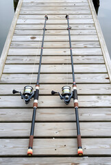 Fototapeta premium Recreation and leisure, two fishing rods with spinning reels resting on a wooden pier for outdoor hobby and travel lifestyle during summer vacation