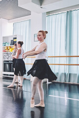 Young female ballerina practicing port de bras in bright ballet studio © TRAVELARIUM