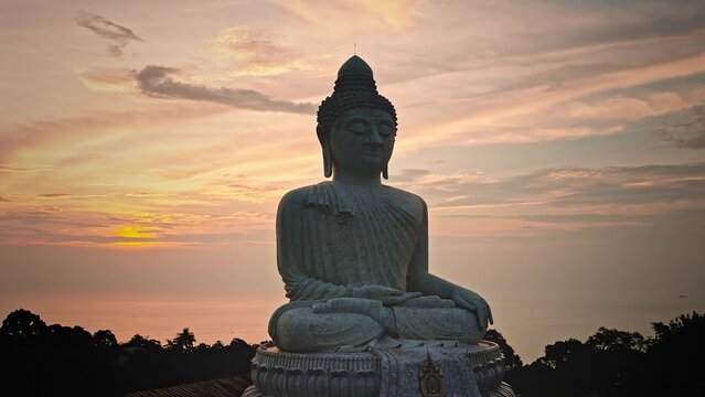 Aerial view of the Big Buddha statue at sunset with a view of the ocean and lush greenery in Phuket, Phuket, Thailand.