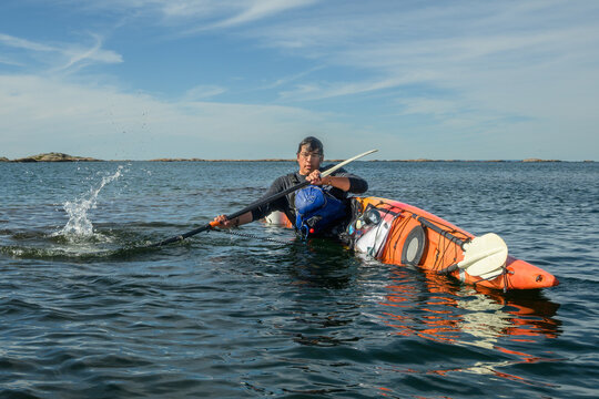 Sea kayaker braces hard with a burst of spray as his kayak heels over during skills practice with copy space on Georgian Bay, Ontario, Canada