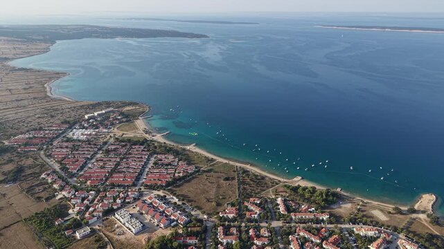 Curving aerial flight along a coastal settlement and sweeping bays in Croatia