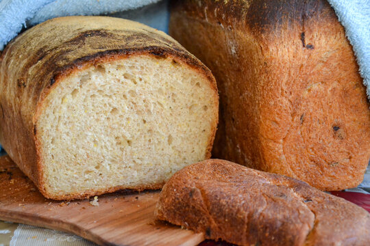 Fresh homemade bread loaves with sliced bread on wooden board