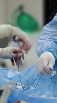 Cardiac catheterization in cath lab, faceless medical team inserting a catheter over a guidewire and preparing a balloon inflation device for angioplasty