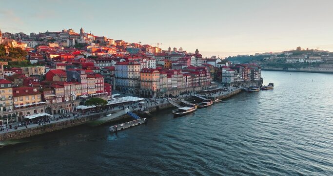 Aerial view of the historic Ribeira district along the Douro River with colorful buildings, traditional rabelo boats, and stone embankments in Porto, Porto, Portugal.
