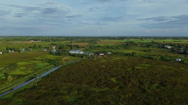 A breathtaking aerial view of lush paddy fields and rice paddies stretching across the Sabah countryside, with the iconic Mount Kinabalu rising majestically in the background at dawn.