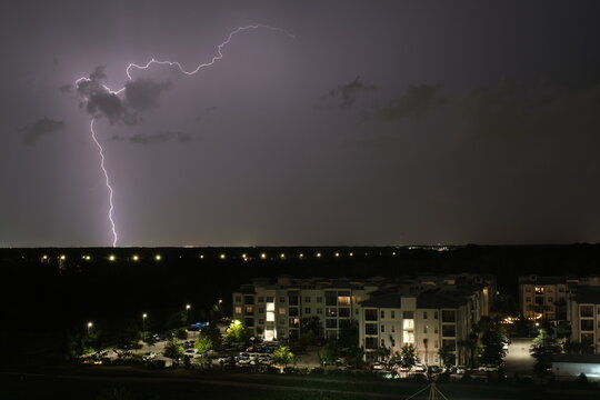 Powerful forked lightning strikes the horizon beyond apartment