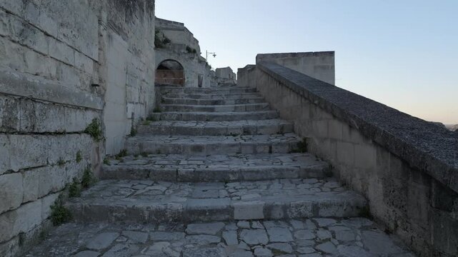 Aerial view of ancient stone stairs in the historic Sassi di Matera, featuring weathered limestone steps and rustic architecture in Matera, Basilicata, Italy.