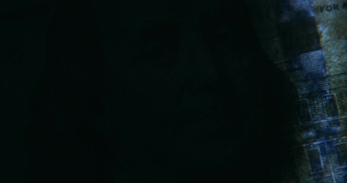 Extreme macro close-up of a hundred US dollar banknote in dark surroundings, illuminated from beneath by a scanner light. Suitable for finance, banking, currency, wealth, economy, authentication.