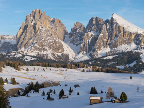Alpe di Siusi in the Dolomites shows snowy landscape with mountain peaks and clear sky. Winter tourism is popular in this area.