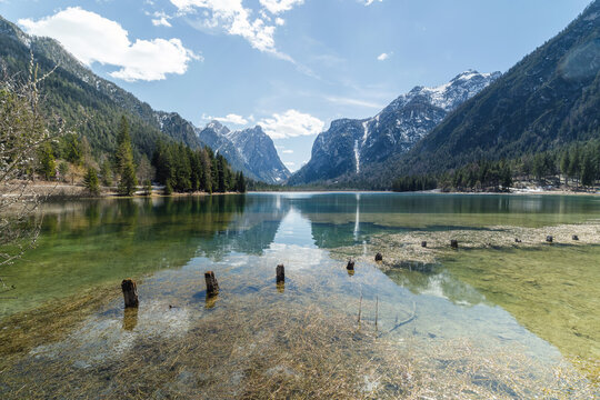 Snow covers mountains surrounding Toblacher See, an alpine lake in the Dolomites, Italy. The scene shows winter beauty in the area.