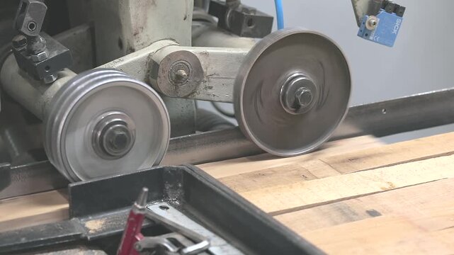 Four-sided woodworking moulder machining a wooden board in an automated production line. Close-up of modern woodworking technology in a factory.