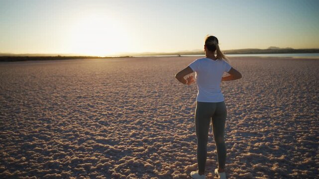 Back view of a serene woman practicing tai chi exercises in a stunning salt lake desert at sunset, embodying concepts of mindfulness, meditation, balance, and a healthy lifestyle