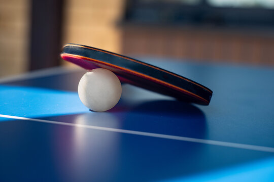 Table tennis paddle and ball on blue ping pong table