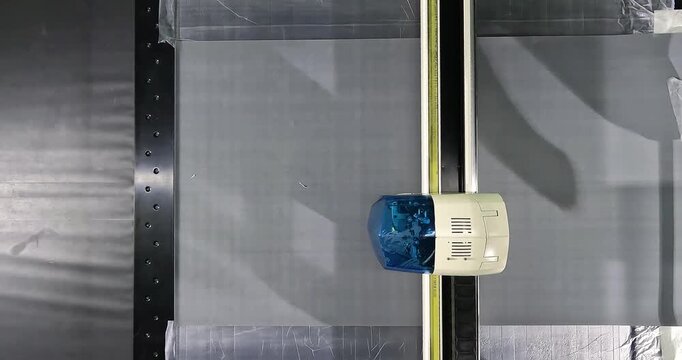 Automated Production Process Using CNC Cutting Machine. Automated cutting of grey upholstery fabric on a CNC plotter. Fabric cutting process on a CNC machine in a modern production workshop. Close-up