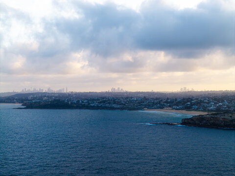 Aerial view of the coastline at Dee Why with the distant Sydney skyline visible under a cloudy sky in Dee Why, New South Wales, Australia.