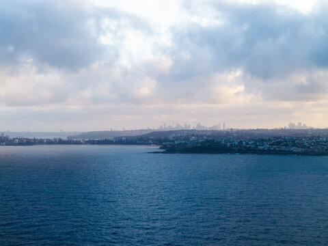 Aerial view of the coastline and residential area of Dee Why with the distant Sydney skyline under a cloudy sky in Dee Why, New South Wales, Australia.