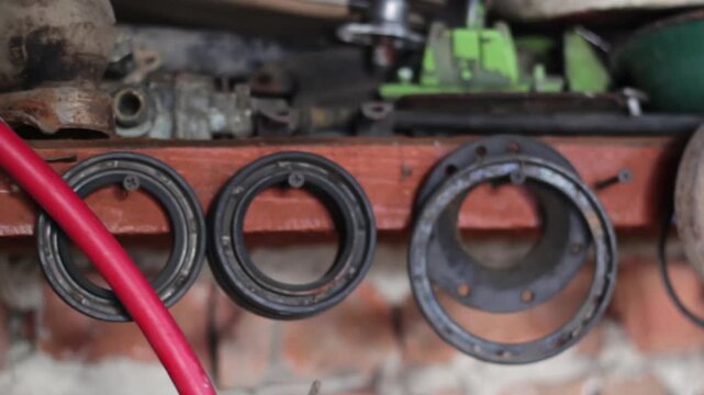Horizontal close-up shot of old metal car parts, bolts, and tools hanging on a wall in a workshop. Garage and repair concept
