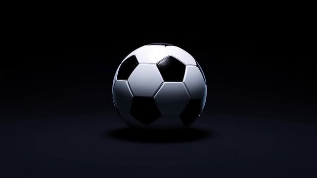 Slow zoom tracking of soccer ball rotating and hovering on dark studio floor with spotlight closeup