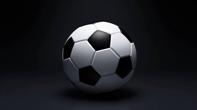 Slow motion tracking shot of soccer ball rotating and rolling across dark studio floor